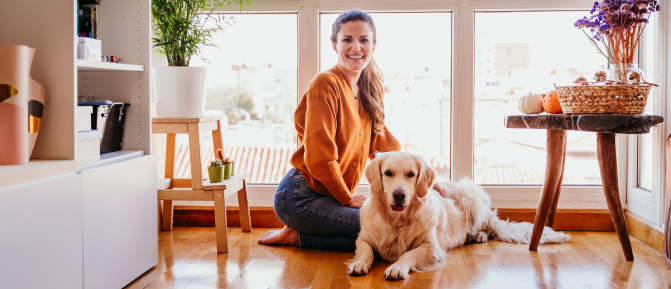 Donna seduta a terra accanto al suo cane in un ambiente domestico luminoso, simbolo del legame uomo-animale e dei benefici della pet therapy sul benessere psicofisico.