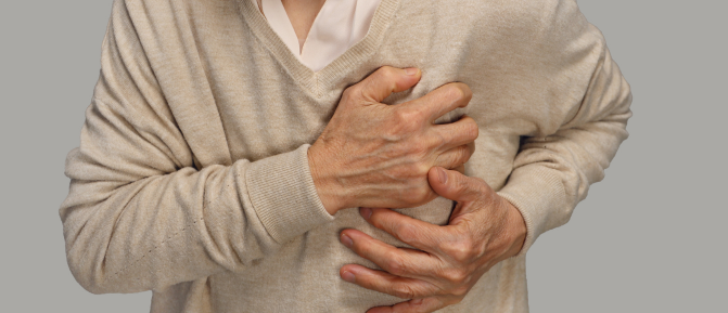 Donna anziana con la mano sul petto in segno di dolore o palpitazioni, immagine rappresentativa dei sintomi delle aritmie cardiache.