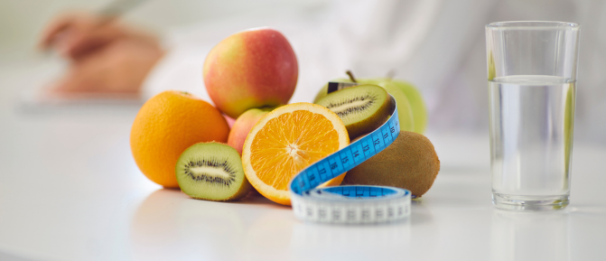 Frutta fresca, metro da sarta e bicchiere d’acqua su un tavolo, immagine dedicata al servizio di consulenza nutrizionale in Farmacia